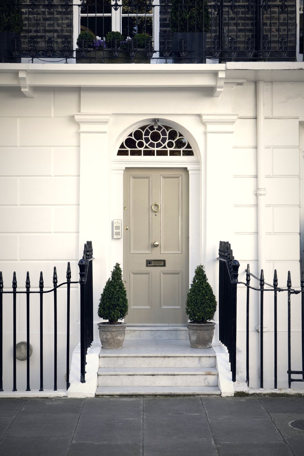 A dark navy panelled front door with polished brass hardware, lit at dusk
