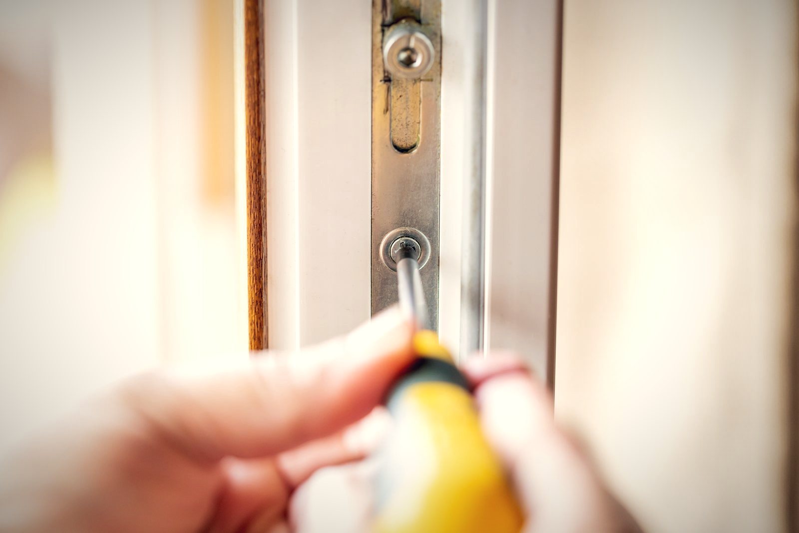 Multipoint locking mechanism along the edge of a white uPVC door being repaired